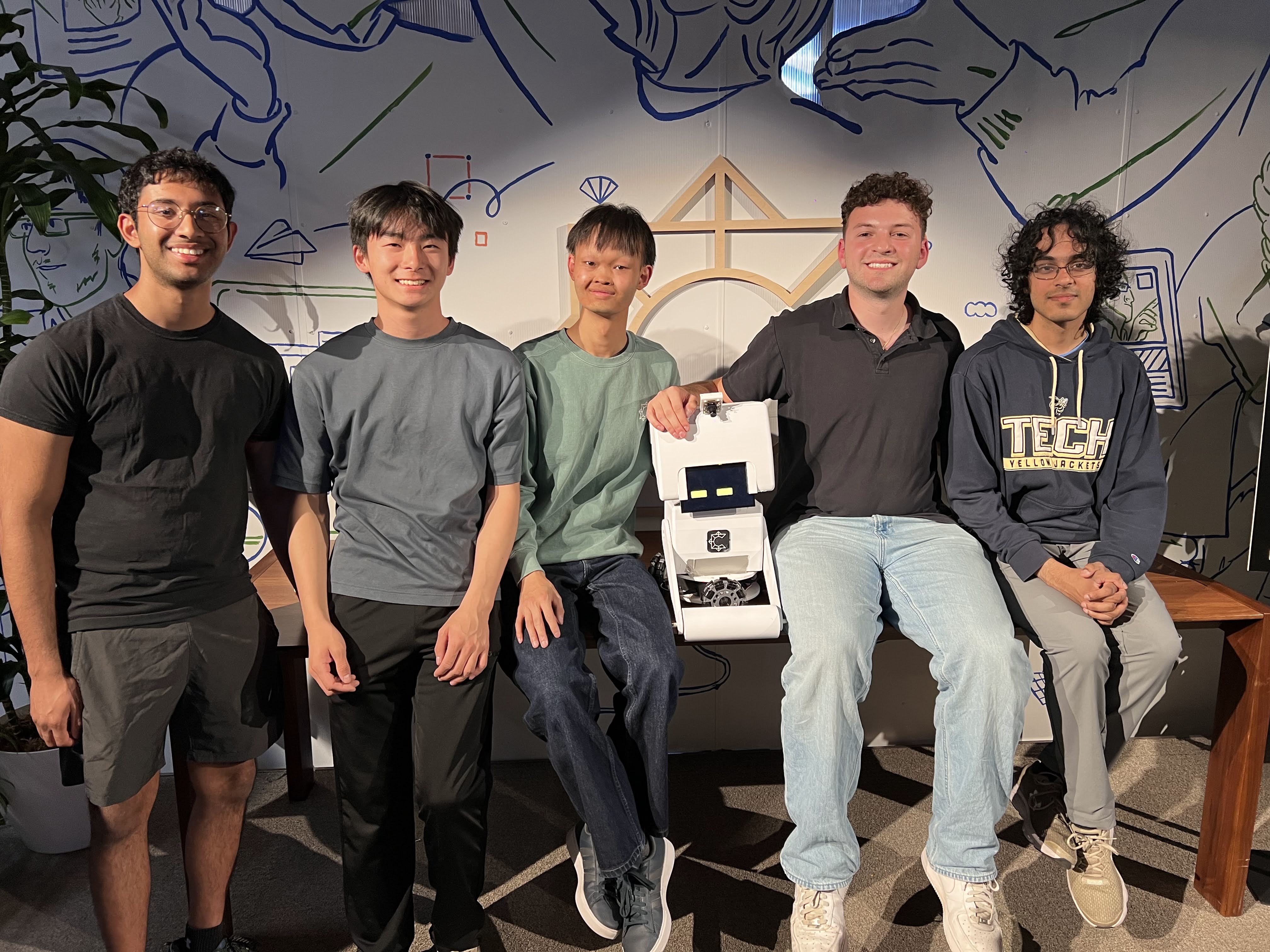 The five-person team behind MoBot, with the robot, in front of a mural at South Park Commons