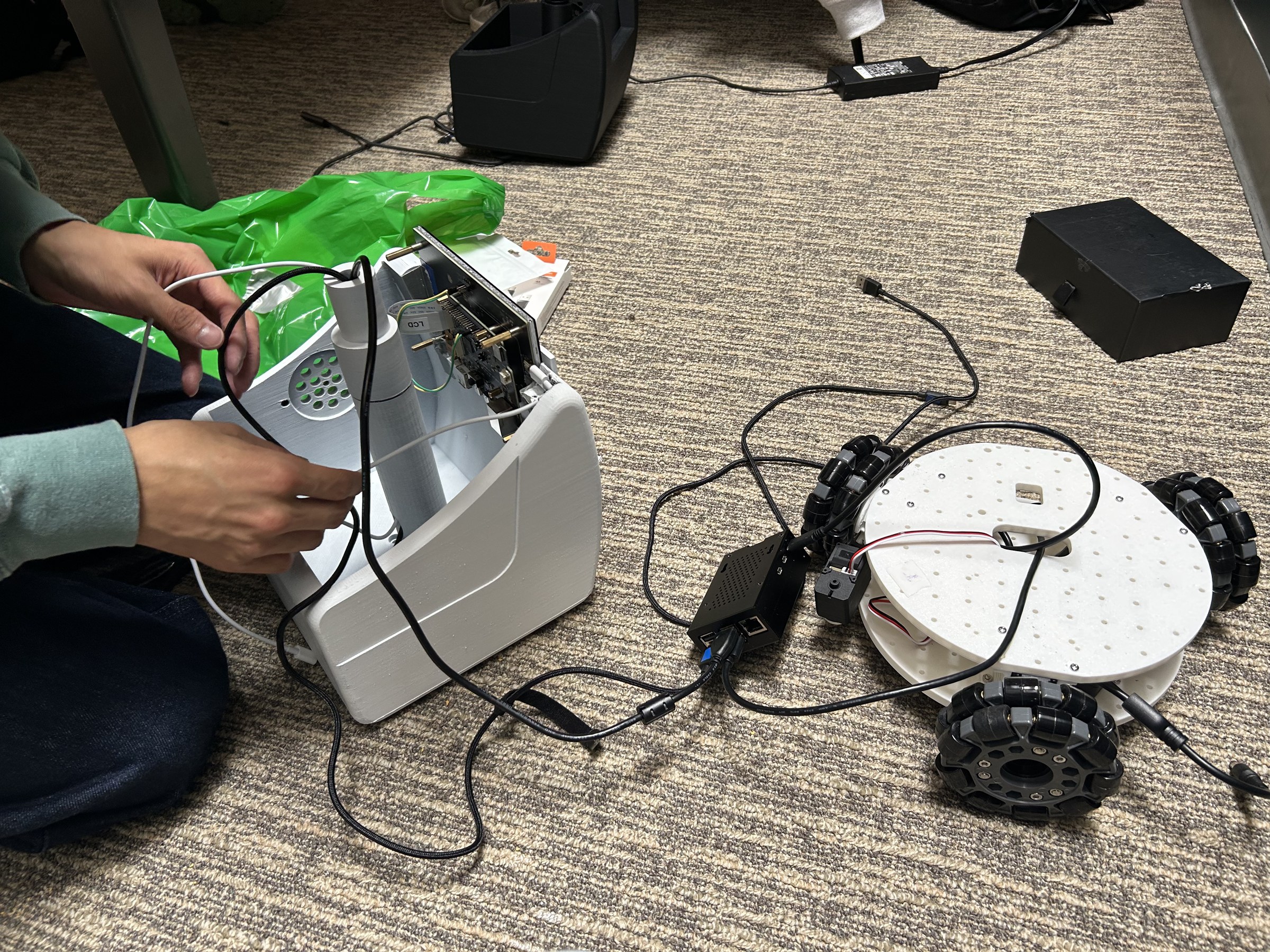 MoBot's wheeled base and printed body being wired together on the floor