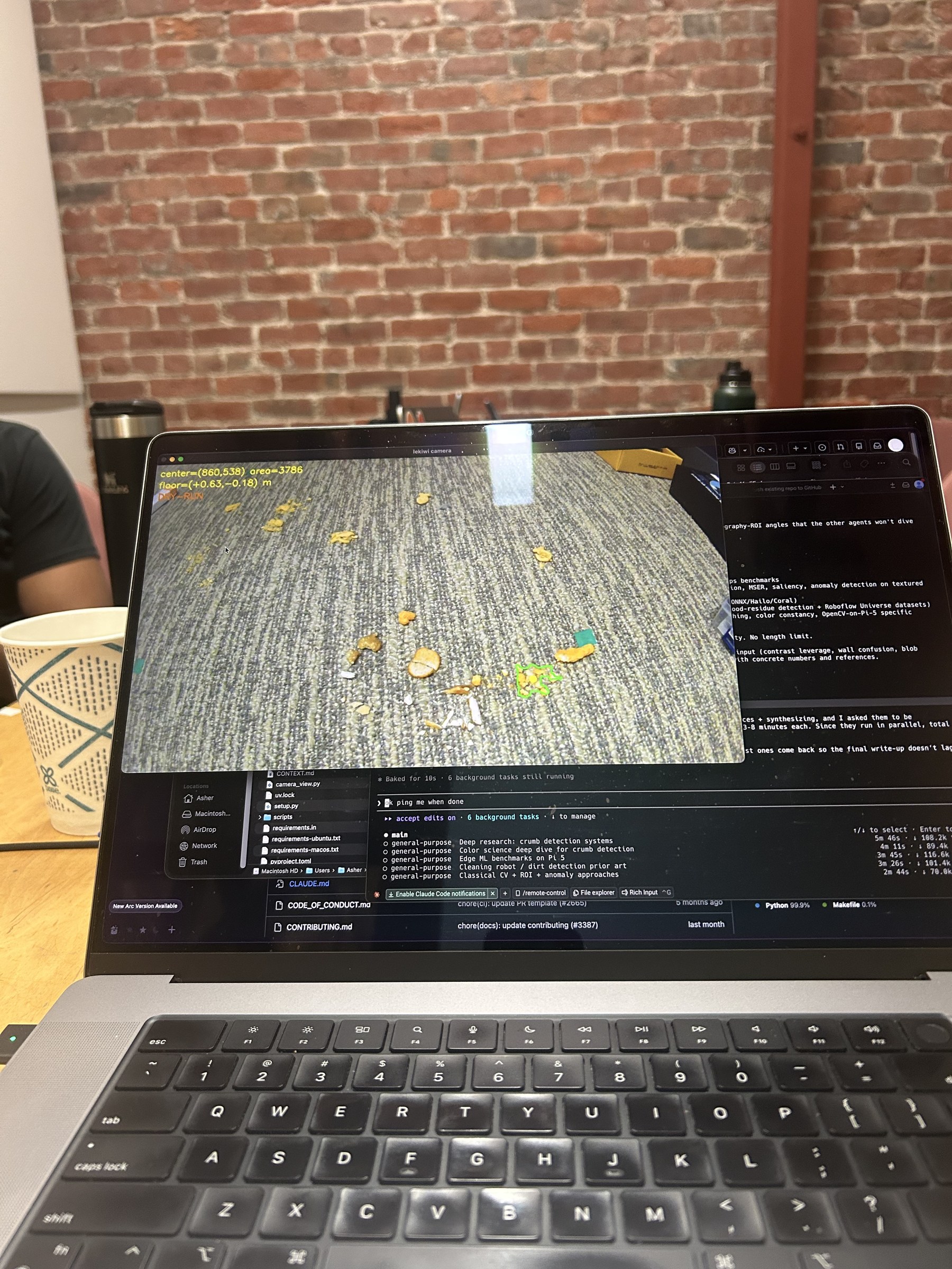A laptop showing MoBot's OpenCV vision feed, with detected messes highlighted on the carpet